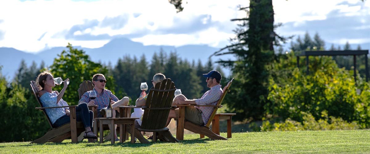 Fairsing Vineyard Guests enjoying estate wines and vineyard views beneath the shade of a Douglas fir tree in Oregon's Willamette Valley
