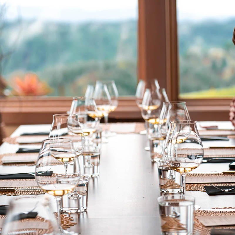 Glasses and a set table greet Guests for a seated tasting near the window at Fairsing Vineyard in Oregon's Willamette Valley