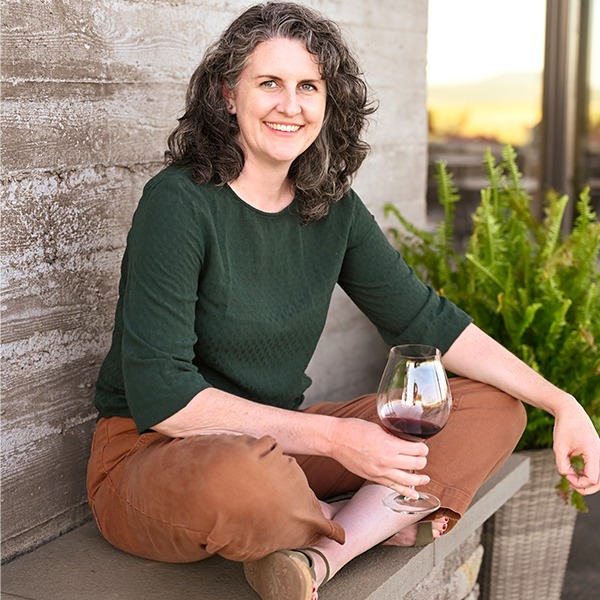 Fairsing Vineyard General Manager Meara McNally Butler sits on the stone wall outside of the sustainably-designed tasting room in Oregon's Willamette Valley