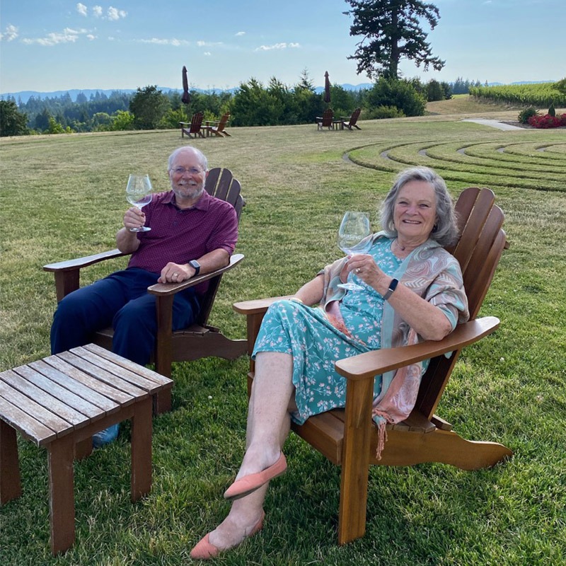 Two people enjoy the sunset at Fairsing VIneyard in Adirondack chairs after a wine dinner
